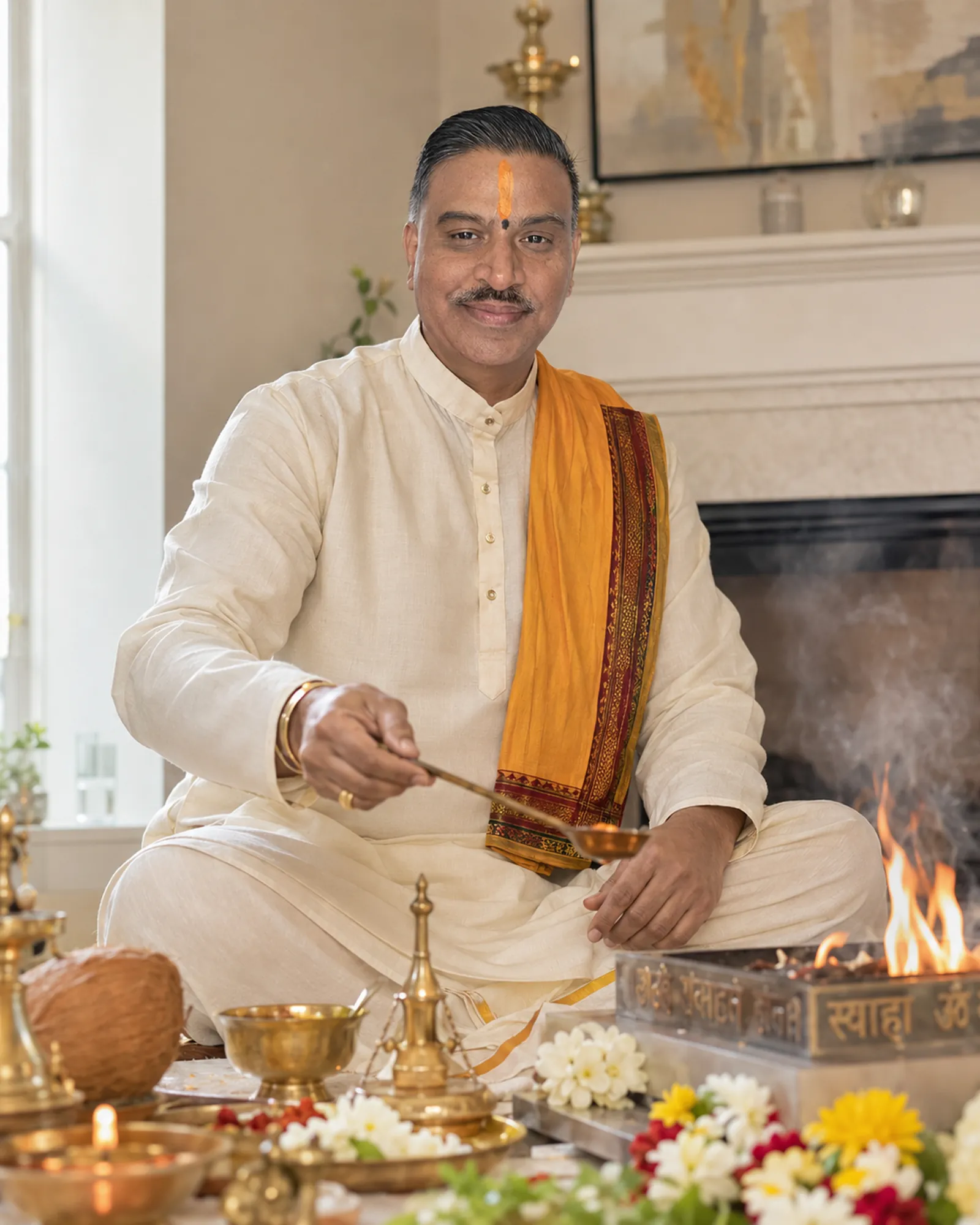Shastri Ji Manishbhai Pandya seated at the sacred fire during a Hindu ceremony